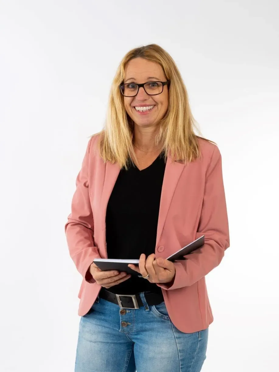 Jennie Ljungdahl i rosa kavaj med en anteckningsbok i händerna